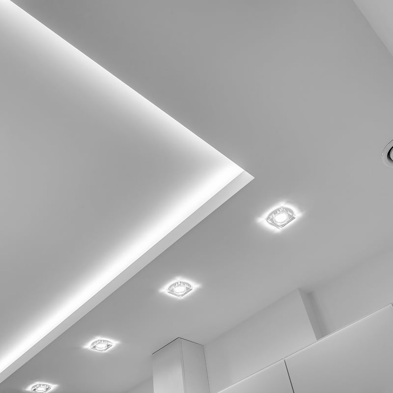Plafond blanc moderne avec éclairage LED encastré et linéaire. Design intérieur minimaliste et lumineux. Luminaires carrés, lumière diffuse.